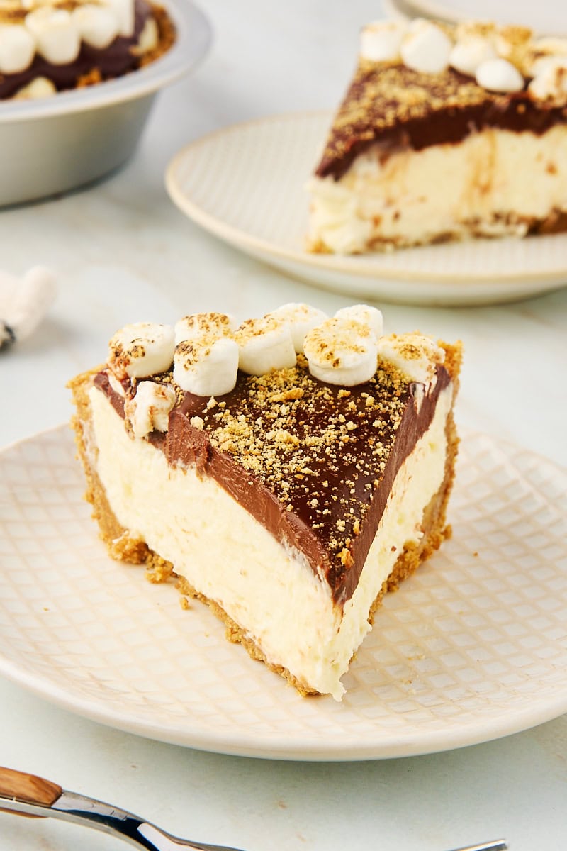 a slice of s'mores pie on a white and beige plate with more pie in the background