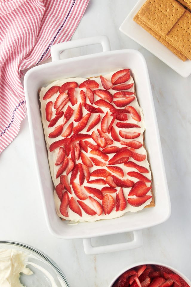 Overhead view of strawberries layered on top of cream for strawberry icebox cake