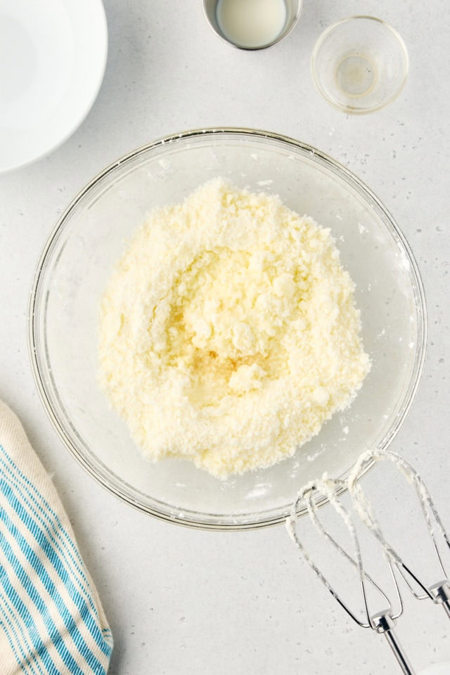 overhead view of milk added to creamed butter and confectioners' sugar