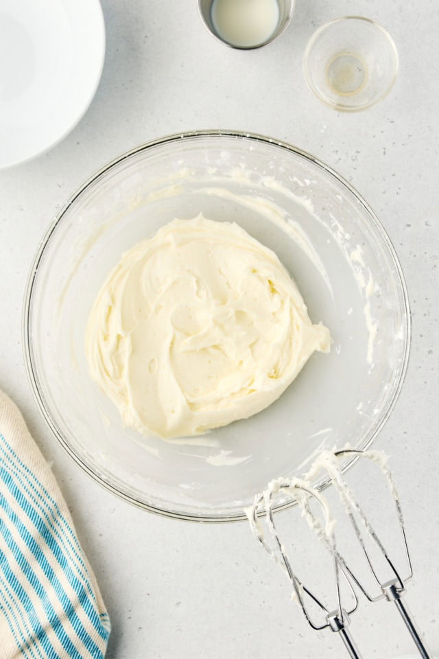 overhead view of mixed vanilla buttercream frosting in a glass mixing bowl