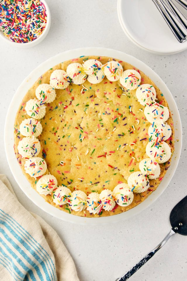 overhead view of sugar cookie cake decorated with piped frosting and sprinkles