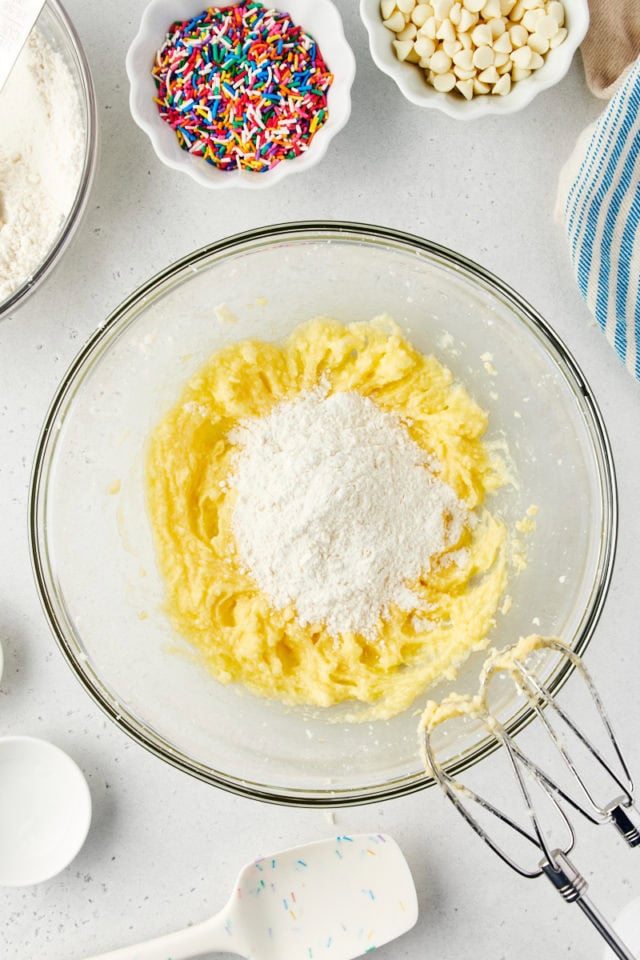 overhead view of dry ingredients added to wet ingredients for sugar cookie cake