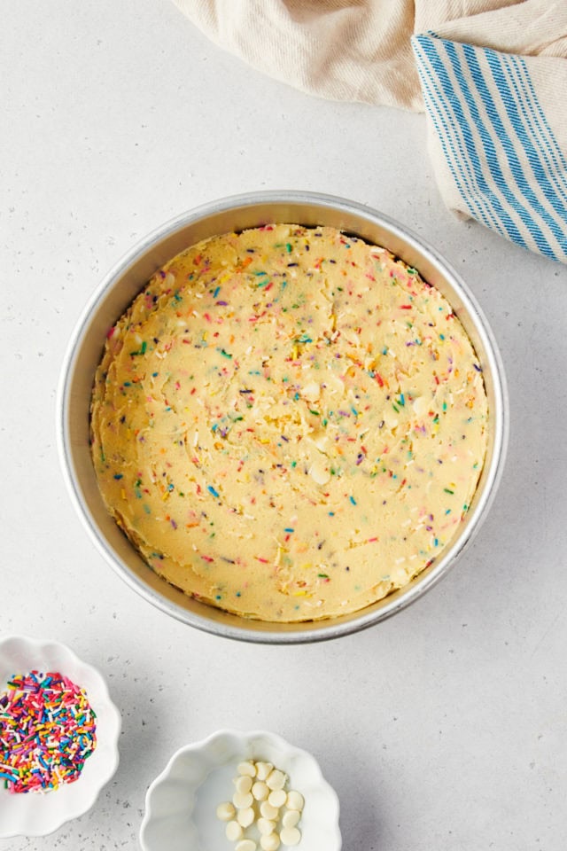 overhead view of sugar cookie cake dough spread in a round cake pan