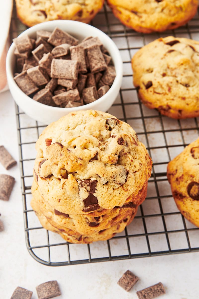 three thick chocolate chip cookies stacked on a wire cooling rack