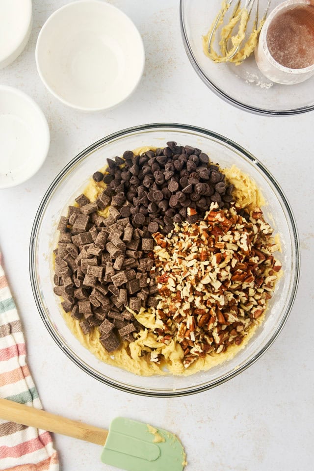 overhead view of chocolate chips and nuts added to cookie dough