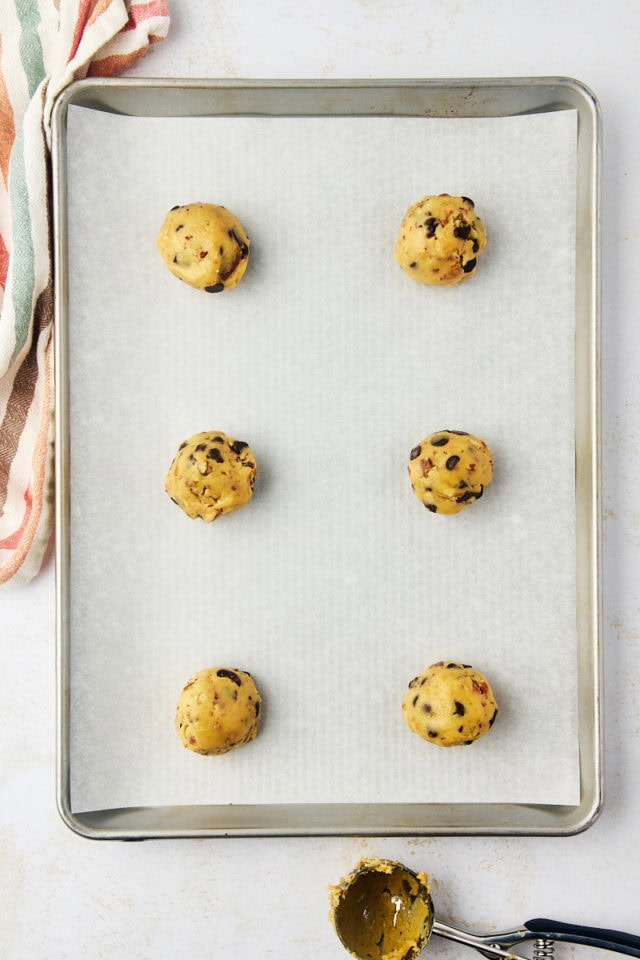 overhead view of portioned thick chocolate chip cookie dough balls on a lined baking sheet