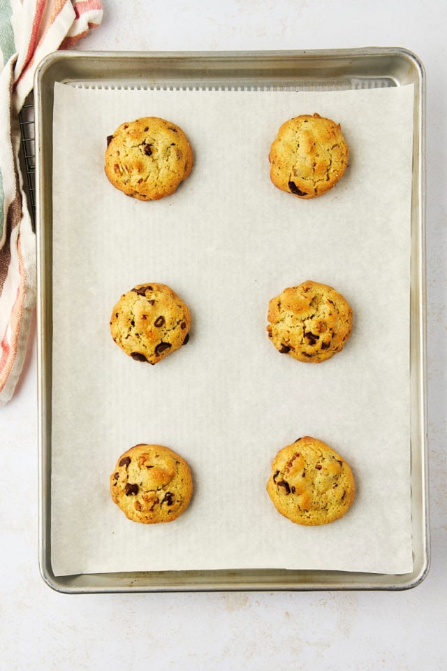 overhead view of freshly baked thick chocolate chip cookies on a lined baking sheet