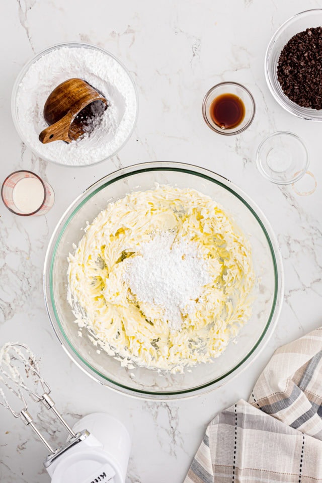 overhead view of confectioners' sugar added to creamed butter and cream cheese