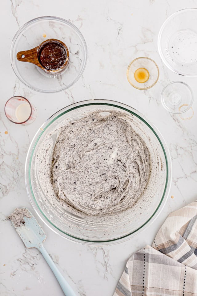 overhead view of cookies and cream frosting in a glass mixing bowl