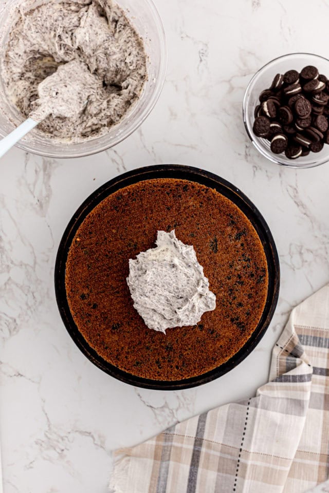 overhead view of frosting dolloped on top of the top layer of cookies and cream cake