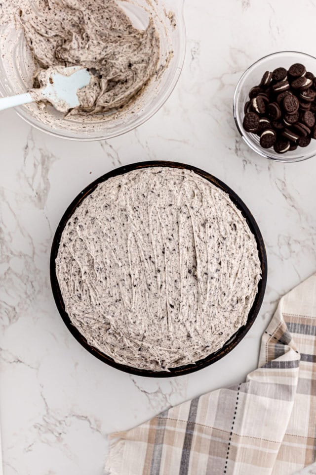 overhead view of frosted cookies and cream cake on a black cake stand