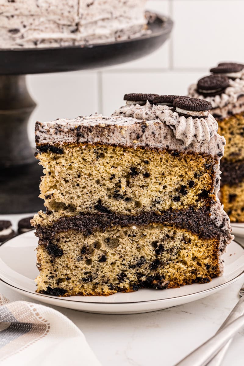 side view of a slice of cookies and cream cake on a white plate