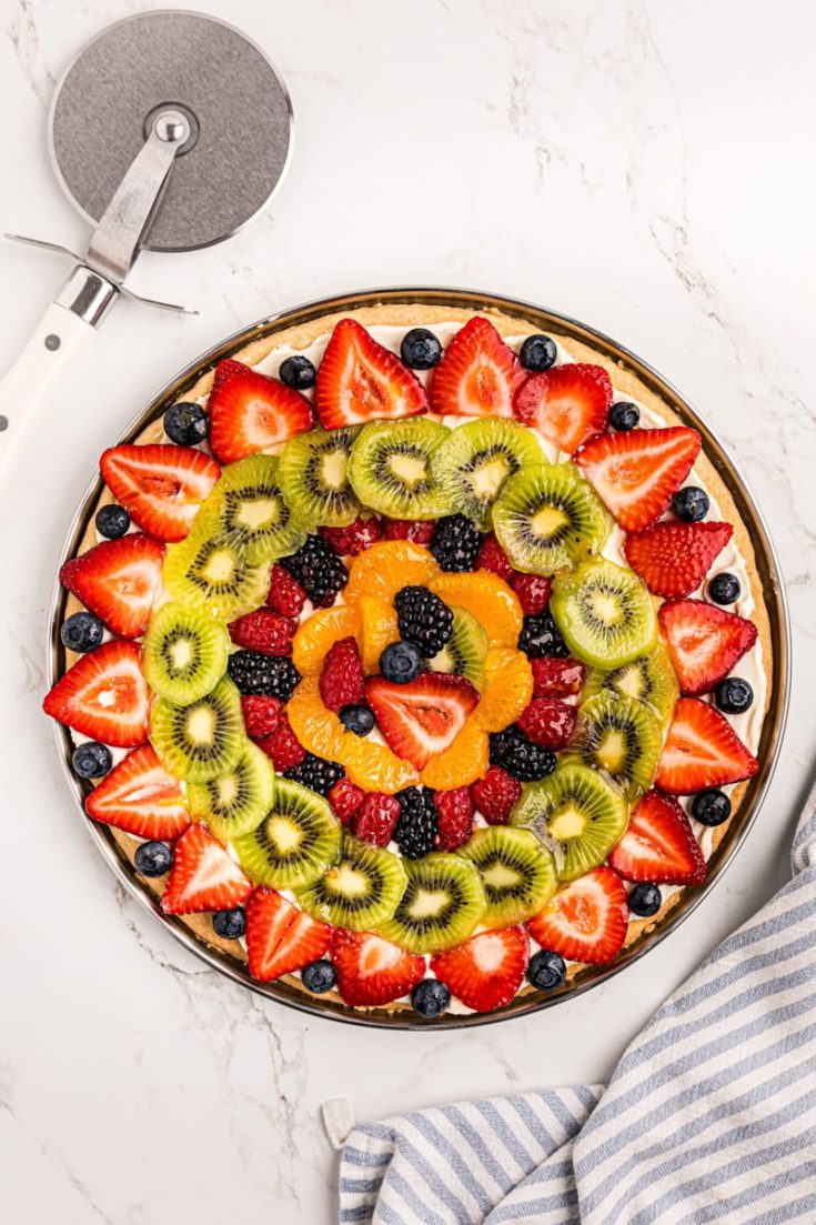 overhead view of fruit pizza on a marble countertop