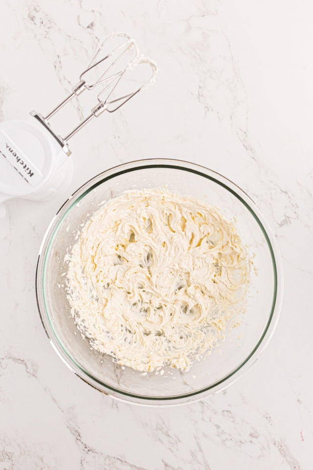 overhead view of mixed cream cheese frosting in a glass mixing bowl