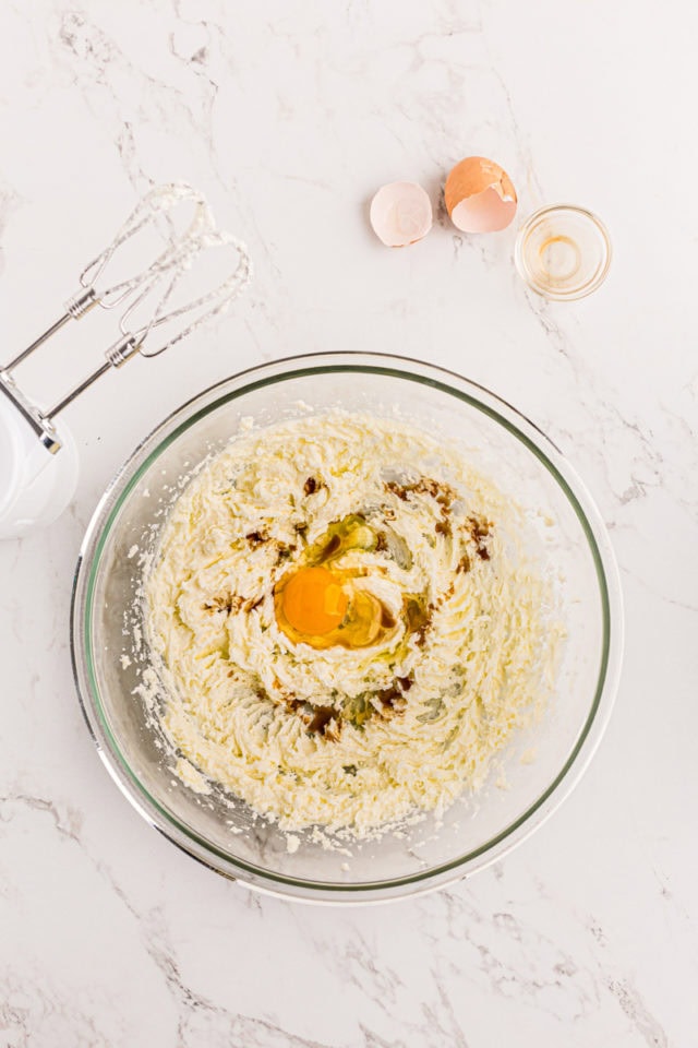 overhead view of egg and vanilla added to creamed butter and sugar in a glass mixing bowl