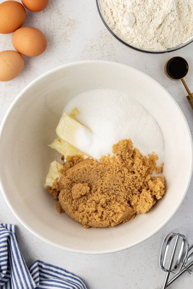 overhead view of butter, sugar, and brown sugar in a white mixing bowl