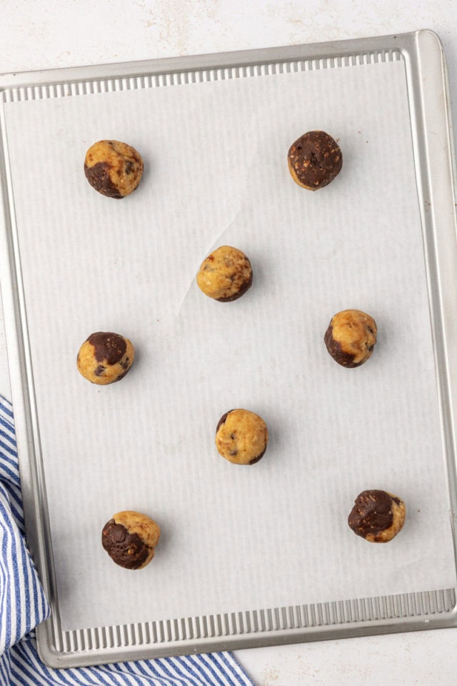 overhead view of marbled chocolate chip cookie dough balls on a parchment-lined baking sheet