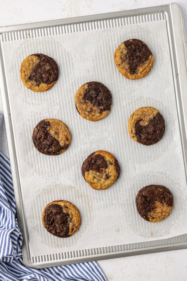 overhead view of freshly baked marbled chocolate chip cookies on a parchment-lined baking sheet