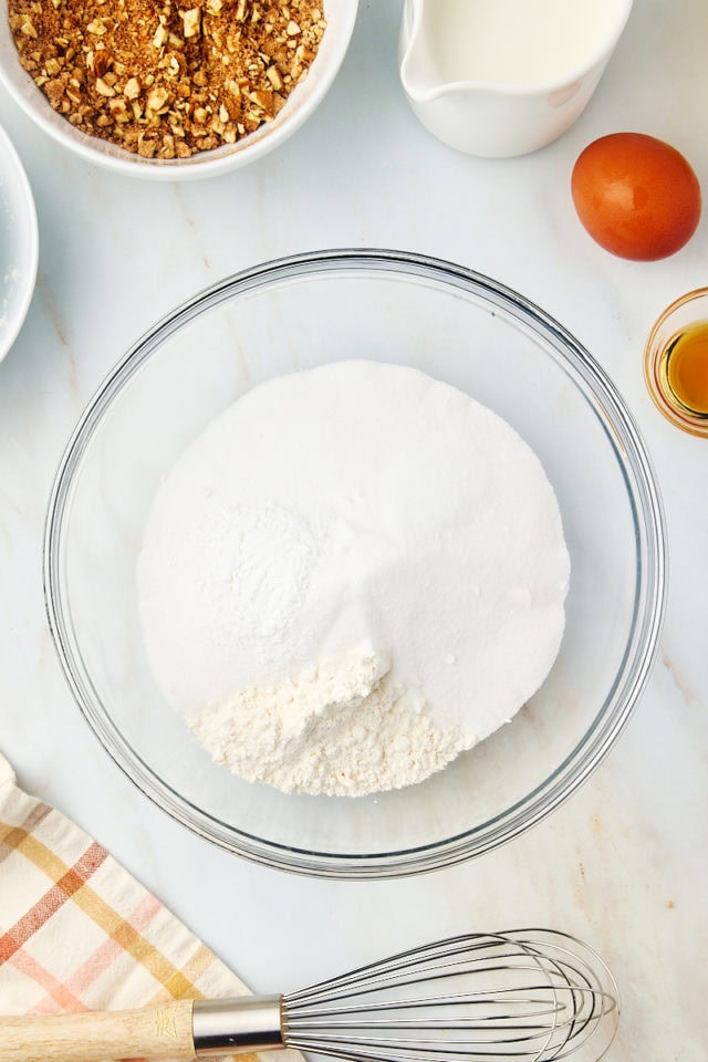 overhead view of sugar, flour, baking powder, and salt in a glass mixing bowl