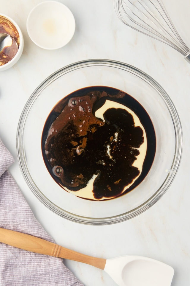 overhead view of condensed milk, vanilla extract, and espresso in a glass mixing bowl