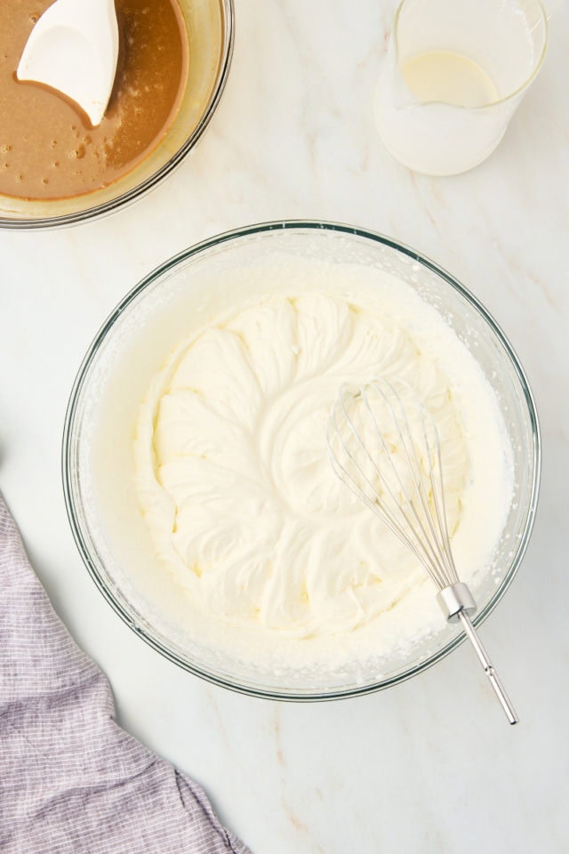 overhead view of whipped cream in a glass mixing bowl