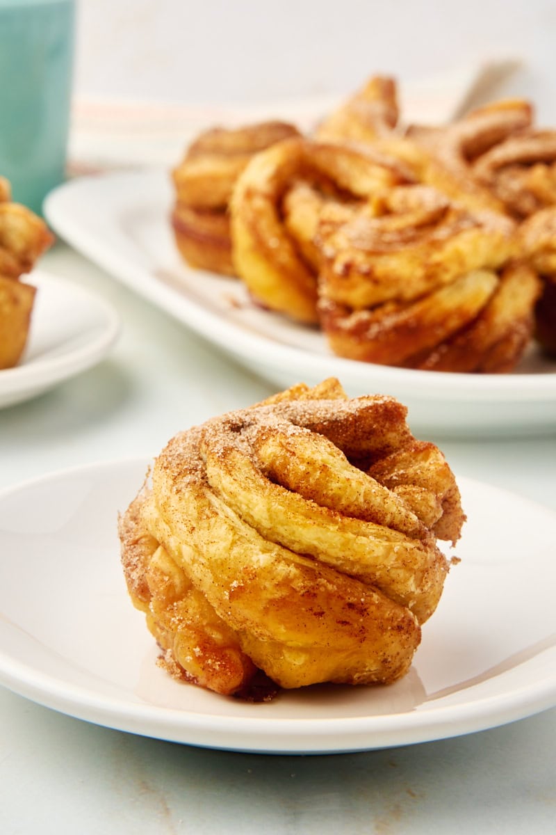 a cruffin on a white plate with more cruffins in the background