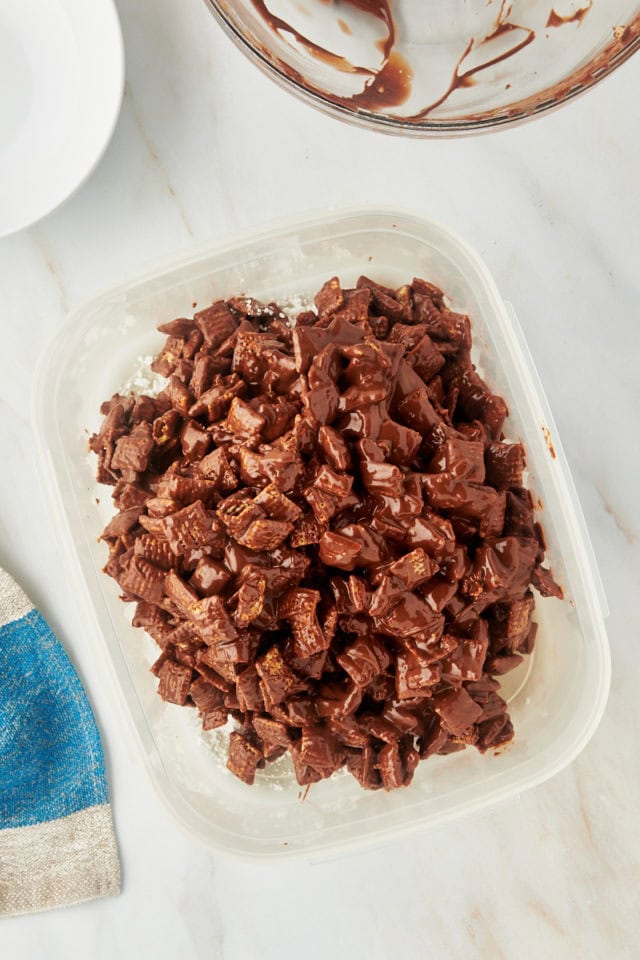 overhead view of muddy buddies mixture in a container with confectioners' sugar