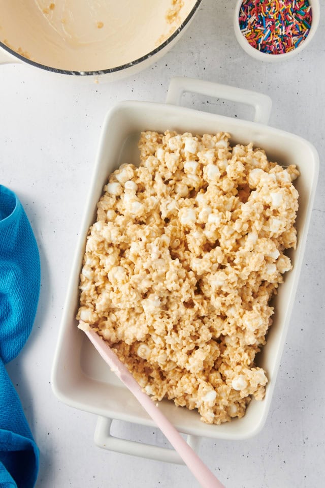 overhead view of rice crispy treats being spread in a pan