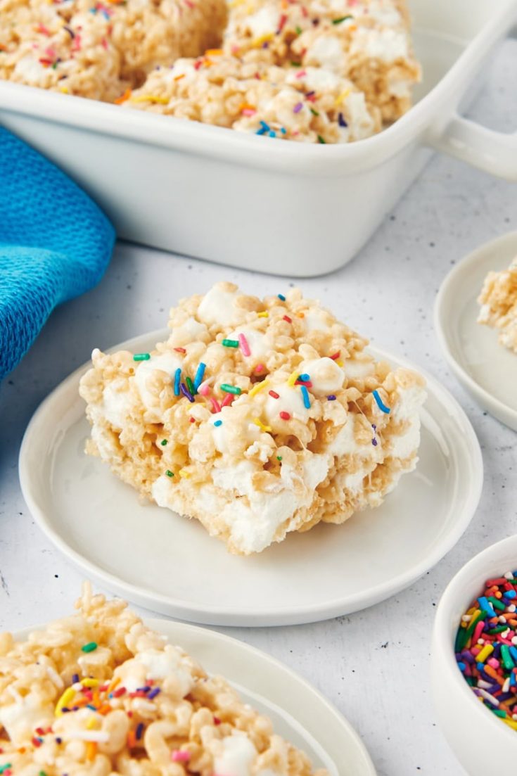 a rice crispy treat on a white plate with more treats surrounding