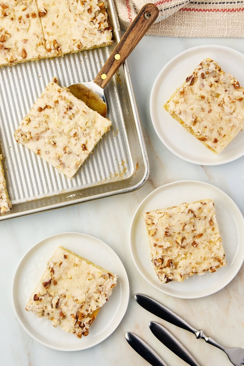 slices of white Texas sheet cake on white plates and on a baking sheet