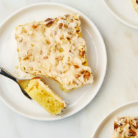 overhead view of a slice of white Texas sheet cake on a white plate with a bite on a fork