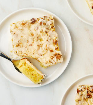 overhead view of a slice of white Texas sheet cake on a white plate with a bite on a fork