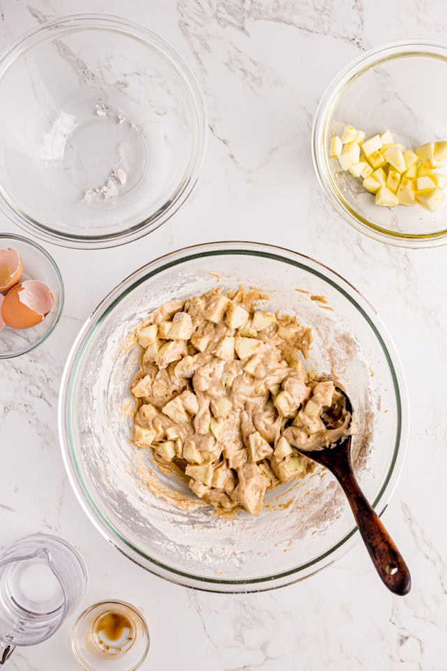 overhead view of mixed apple fritters batter in a glass mixing bowl