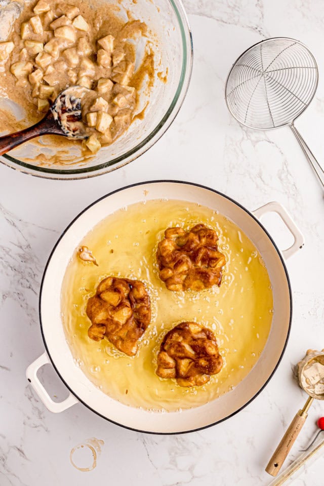 overhead view of cooked apple fritters in a pot of oil