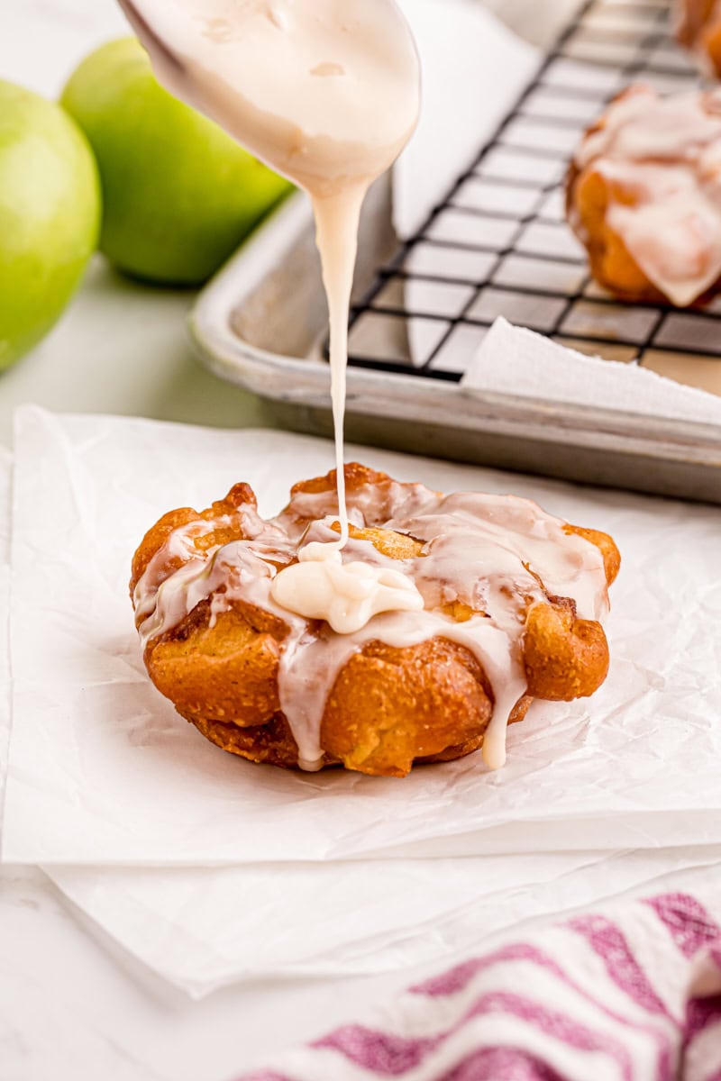 maple glaze being spooned over an apple fritter