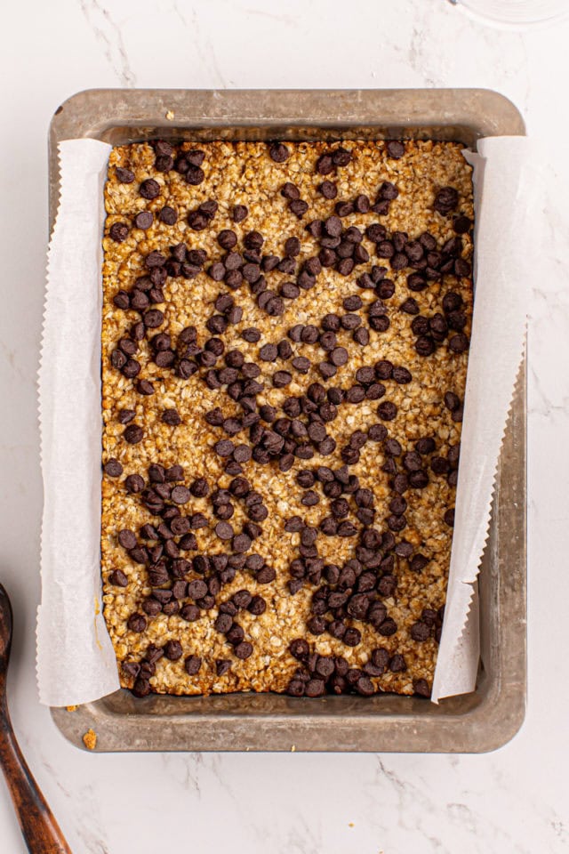 overhead view of chocolate chips on top of caramel oatmeal bars crust