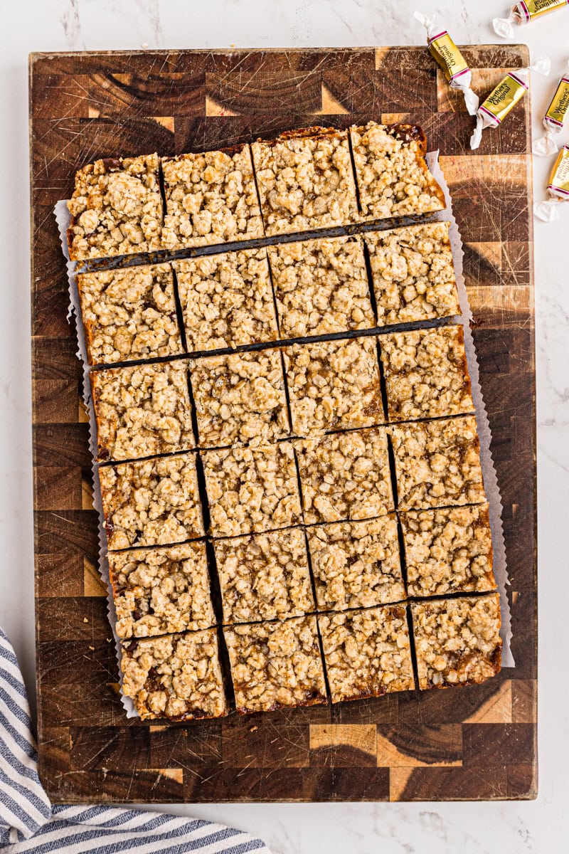 overhead view of caramel oatmeal bars cut into squares on a wooden cutting board