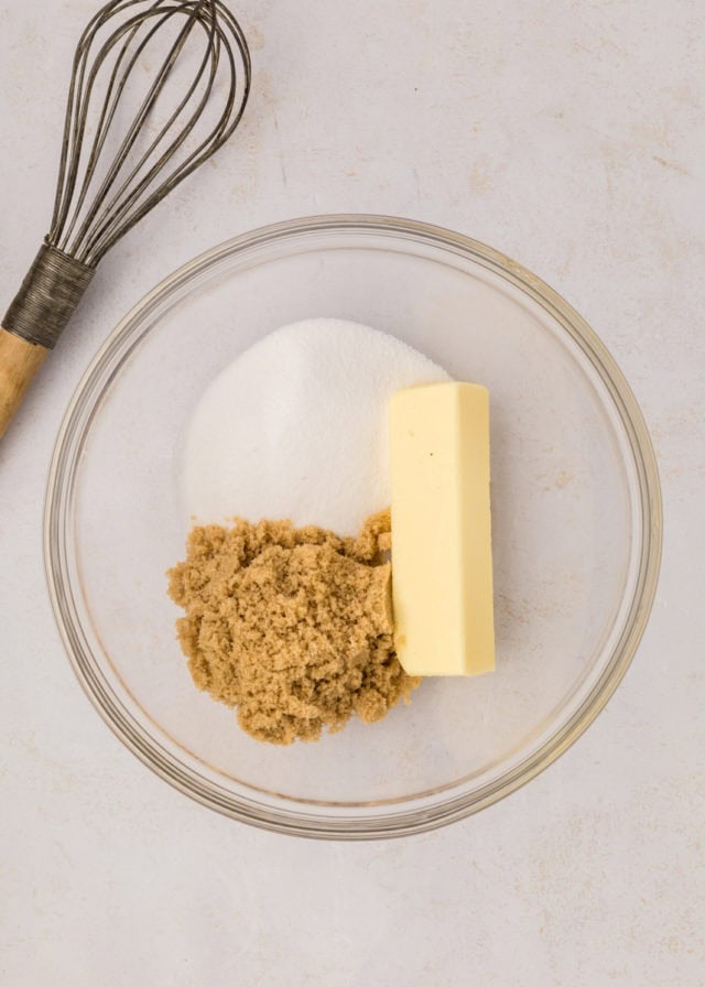 overhead view of butter, sugar, and brown sugar in a glass mixing bowl