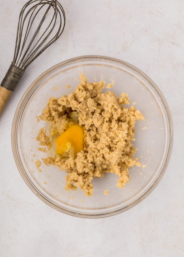 overhead view of egg added to creamed butter and sugar