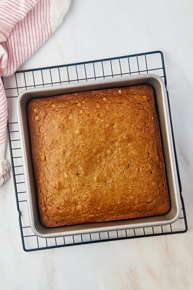 overhead view of freshly baked applesauce cake in a square pan on a wire rack