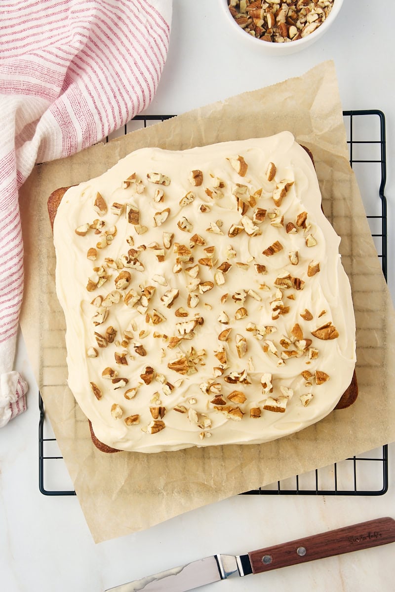 overhead view of frosted applesauce cake on parchment paper on a wire rack