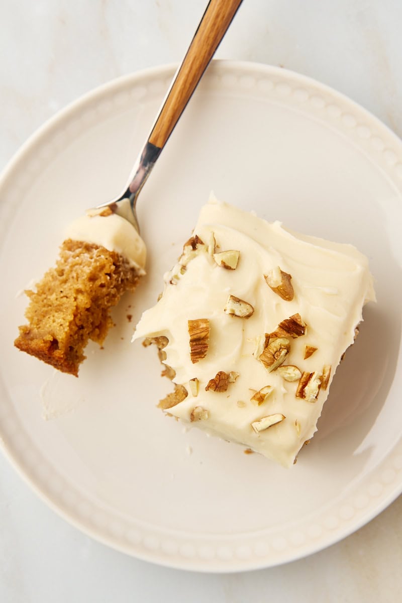 overhead view of a slice of applesauce cake on a plate with a bite on a fork