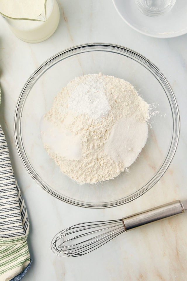 overhead view of flour, baking powder, sugar, and salt in a glass mixing bowl