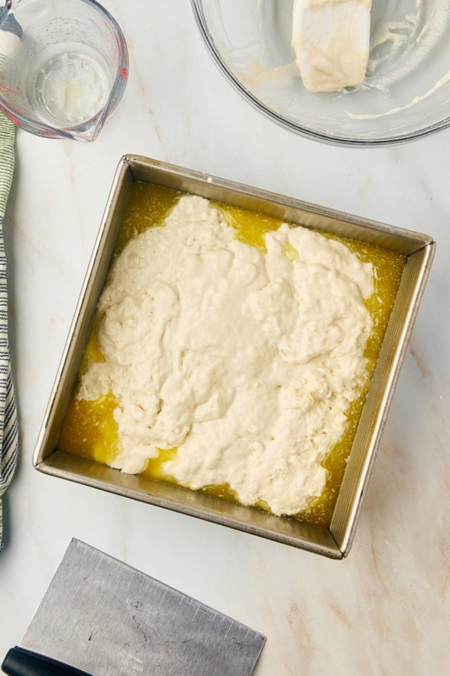 overhead view of butter swim biscuits dough in a baking pan filled with melted butter