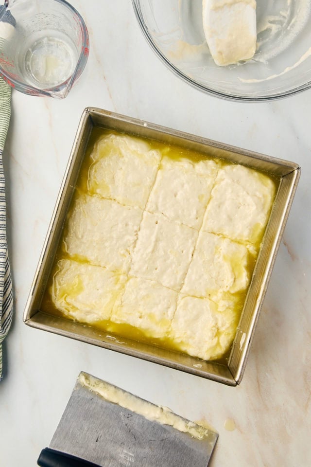 overhead view of scored butter swim biscuits in a metal baking pan