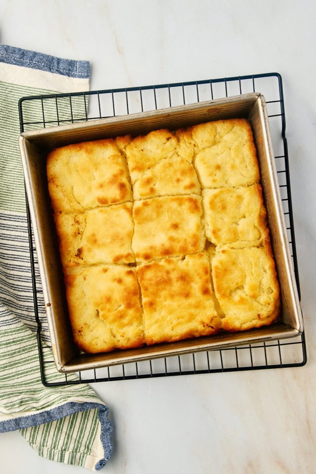 overhead view of freshly baked butter swim biscuits in a baking pan on a wire rack