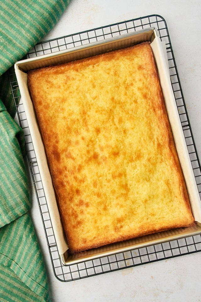 overhead view of freshly baked gooey butter cake in a baking pan on a wire cooling rack