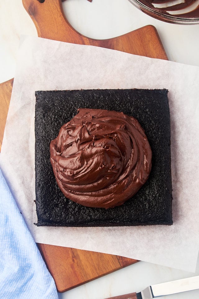 overhead view of frosting added to the top of chocolate cake