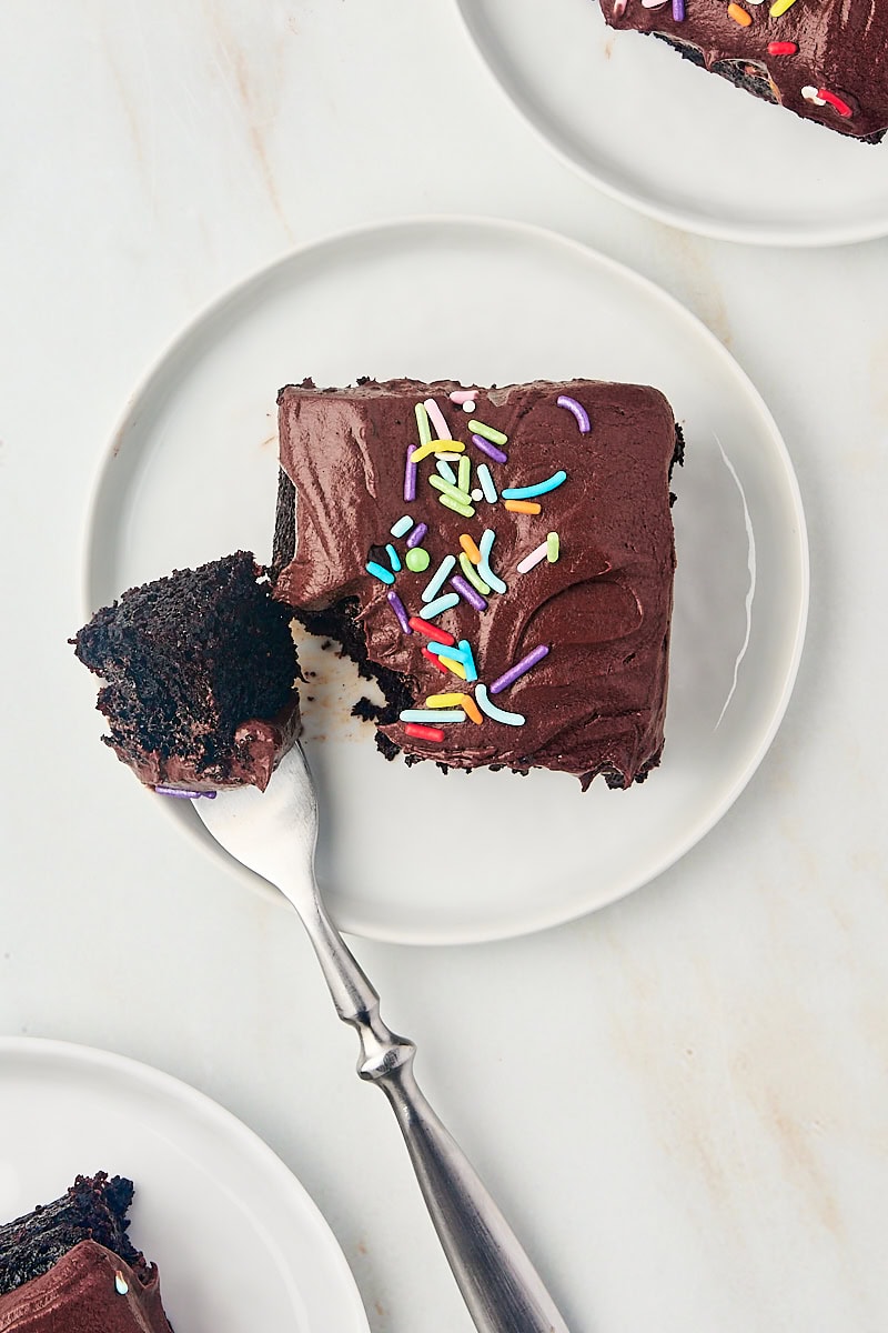 overhead view of a slice of one-bowl chocolate cake on a white plate with a bite on a fork