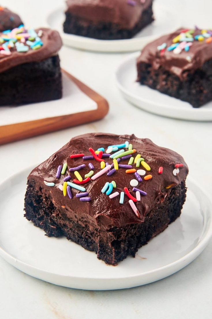 slice of one-bowl chocolate cake on a white plate with more cake in the background